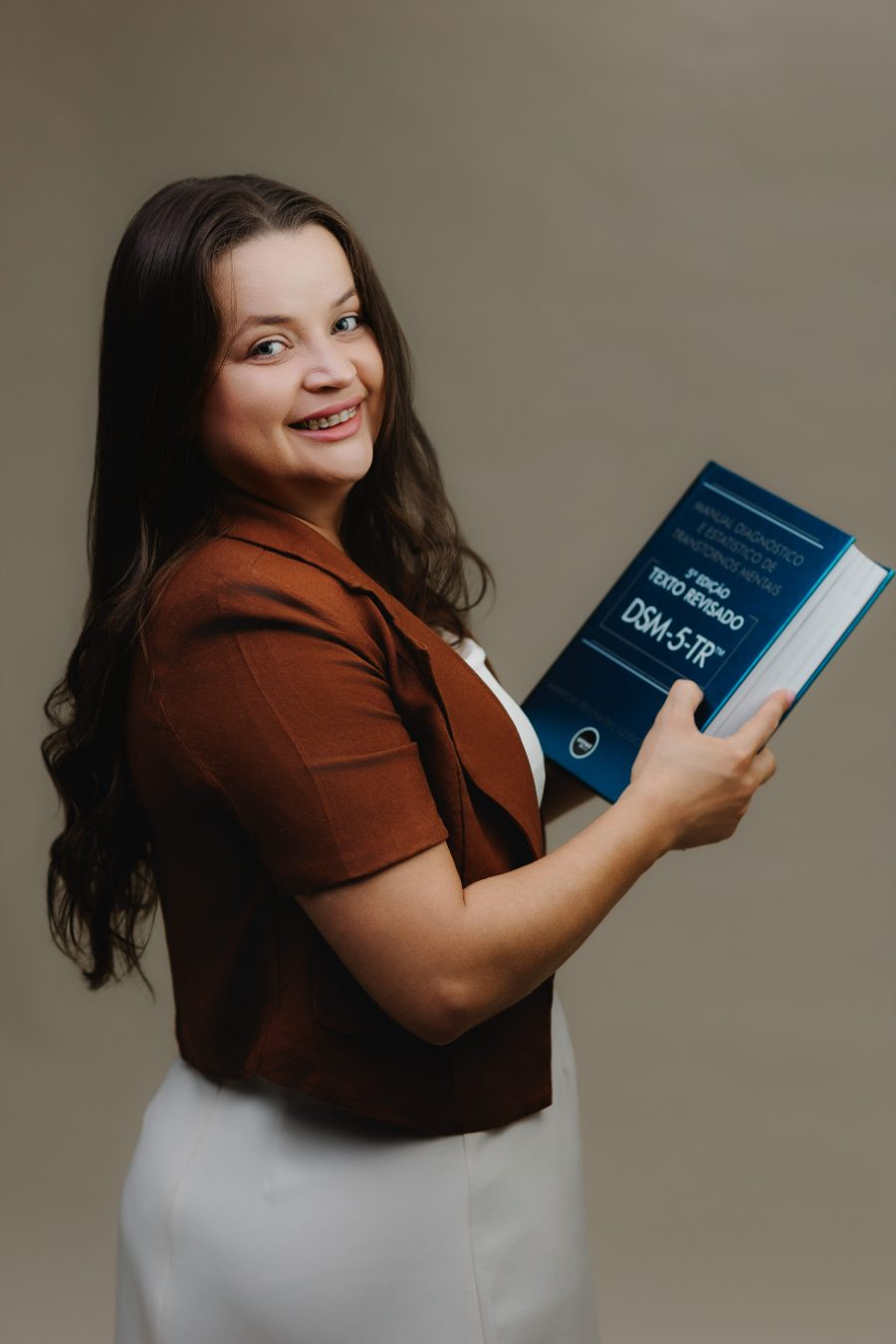 Claudiane Albarracin segurando o Manual Diagnóstico e Estatístico de Transtornos Mentais, DSM-5-TR.